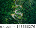 Top-down aerial view of curved road passing through lush green mountain forest 143666276