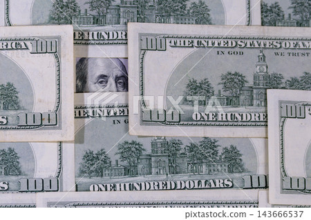 Benjamin Franklin's eyes peeking through scattered hundred dollar bills. Benjamin Franklin's eyes peeking through scattered hundred dollar bills. 143666537