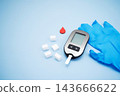 Diabetes concept with blood glucose meter, sugar cubes, blue awareness ribbon and medical gloves on blue background 143666622