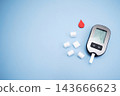 Diabetes concept with blood glucose meter, sugar cubes, blue awareness ribbon and medical gloves on blue background 143666623