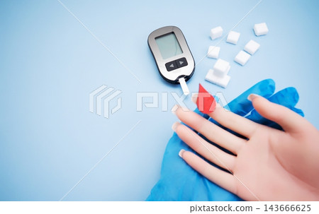 Diabetes concept with blood glucose meter, sugar cubes, blue awareness ribbon and medical gloves on blue background Diabetes concept with blood glucose meter, sugar cubes, blue awareness ribbon and medical gloves on blue background 143666625