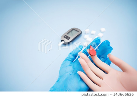 Diabetes concept with blood glucose meter, sugar cubes, blue awareness ribbon and medical gloves on blue background Diabetes concept with blood glucose meter, sugar cubes, blue awareness ribbon and medical gloves on blue background 143666626