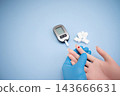 Diabetes concept with blood glucose meter, sugar cubes, blue awareness ribbon and medical gloves on blue background 143666631