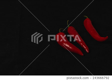 Red chili peppers arranged against a black background Red chili peppers arranged against a black background 143666792