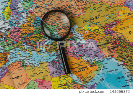 Exploring a world map with a magnifying glass for travel plans Exploring a world map with a magnifying glass for travel plans 143666873