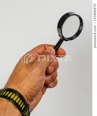 Hand holding a magnifying glass for examination and inspection Hand holding a magnifying glass for examination and inspection 143666879