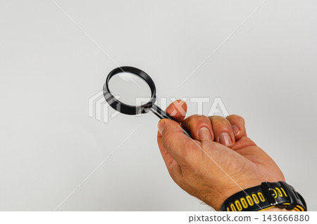 Hand holding magnifying glass for inspection and detailed examination Hand holding magnifying glass for inspection and detailed examination 143666880
