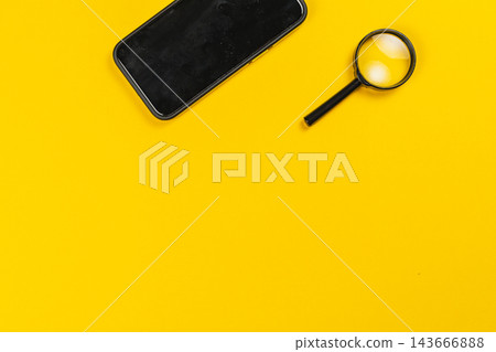 Smartphone and magnifying glass on yellow background for investigation 143666888
