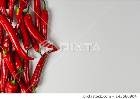 Red chili peppers arranged along the left side on white 143666904