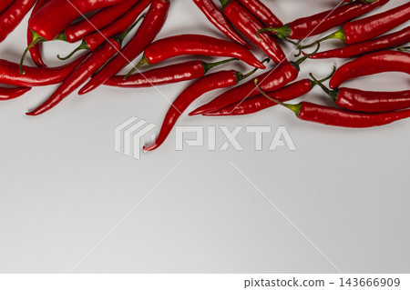 Red chili peppers arranged along the top of a white background Red chili peppers arranged along the top of a white background 143666909