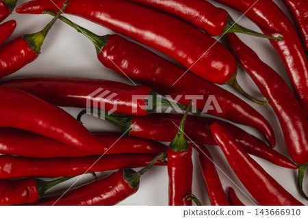 Red chili peppers arranged on a white surface Red chili peppers arranged on a white surface 143666910