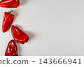Red peppers arranged along the edge of a pale background 143666941