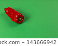 Red sweet pepper resting on a green surface 143666942