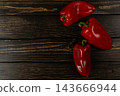 Three red bell peppers on a black wooden surface for cooking 143666944