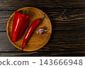 Pepper, chili, and garlic arranged on a wooden board 143666948
