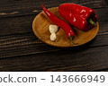Red pepper, chili, and garlic on a wooden plate in a kitchen 143666949