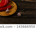 Chili peppers and garlic on a wooden board in a kitchen 143666950