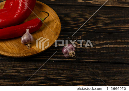 Chili peppers and garlic on a wooden board in a kitchen Chili peppers and garlic on a wooden board in a kitchen 143666950