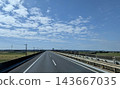 A straight highway through a rural area with a blue sky and white clouds. 143667035