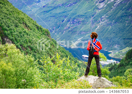 Tourist over Geirangerfjord with norwegian flag Tourist over Geirangerfjord with norwegian flag 143667053