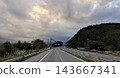 A highway running along a forest in Fujiyoshida City, Yamanashi Prefecture, with a sky full of clouds. 143667341