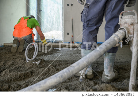 Construction Worker Pouring and Leveling Concrete Screed Floor Indoors Construction Worker Pouring and Leveling Concrete Screed Floor Indoors 143668085