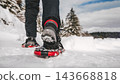 Person Hiking on Snowy Mountain Trail in Snowshoes 143668818