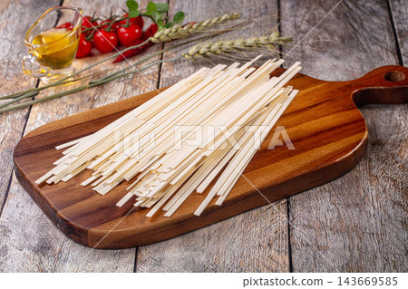 Udon noodles on wooden cutting board with cherry tomatoes and olive oil Udon noodles on wooden cutting board with cherry tomatoes and olive oil 143669585