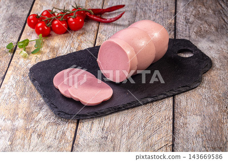 Sliced sausage on black slate with cherry tomatoes and red chili peppers 143669586
