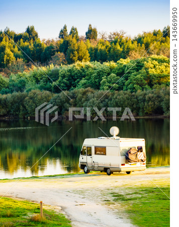 Caravan camping on lake shore with satellite dish on roof 143669950