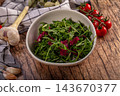Fresh garlic bulbs and cherry tomatoes on vine beside ceramic bowl of arugula and radicchio leaves on rustic wood, healthy salad ingredients 143670377