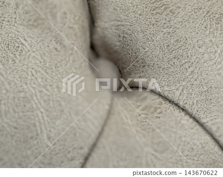 Closeup of soft cream fabric folds forming an abstract textured background with subtle shadows and curves Closeup of soft cream fabric folds forming an abstract textured background with subtle shadows and curves 143670622