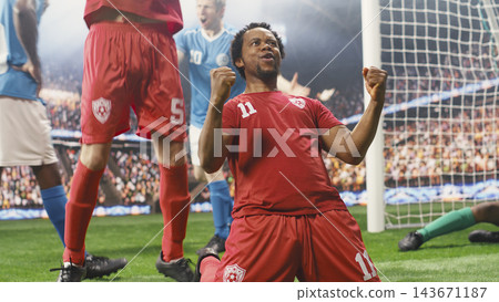 African american red soccer player smiling and celebrating with clenched fists during goal celebration near goal net, joyful reaction on pitch. Red team excitement and win. African american red soccer player smiling and celebrating with clenched fists during goal celebration near goal net, joyful reaction on pitch. Red team excitement and win. 143671187