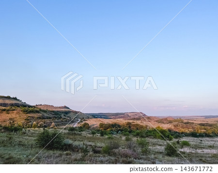 Winding dirt road through rolling hills and open countryside 143671772