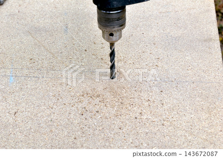 The process of drilling a hole in a wooden board. The process of drilling a hole in a wooden board. 143672087