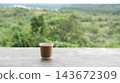 espresso coffee in a paper cup on wooden table with green nature forest view 143672309