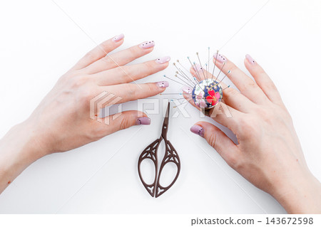 a ring with a small pillow for needles on a hand and scissors on a white background 143672598