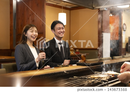 A smiling man and woman sitting at the counter of a restaurant. A smiling man and woman sitting at the counter of a restaurant. 143673388