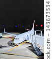 A passenger plane parked at a boarding bridge at a nighttime airport. 143673534