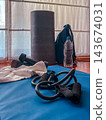 Fitness gear neatly arranged on a blue yoga mat for a home workout: dumbbells, resistance bands, foam roller, towel and water bottle ready for training and recovery 143674031