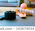 Fitness accessories on a yoga mat, including an ankle weight, reusable water bottle, and towel, emphasizing home workout, wellness, and a healthy lifestyle 143674034