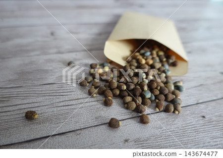 Mole plant seeds spilling from a packet on a rustic wooden table, preparing for spring gardening Mole plant seeds spilling from a packet on a rustic wooden table, preparing for spring gardening 143674477