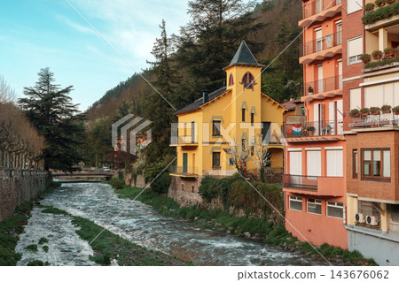 Yellow tower house beside Freser river with forested mountain in Ribes de Fresser Yellow tower house beside Freser river with forested mountain in Ribes de Fresser 143676062