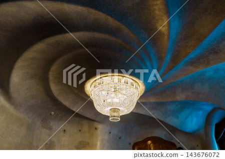 Swirling sculpted ceiling around a crystal chandelier in blue and gold tones at Casa Batllo Swirling sculpted ceiling around a crystal chandelier in blue and gold tones at Casa Batllo 143676072