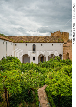 Whitewashed arcaded courtyard with orange trees and crenellated fortress wall at the Alcazar of Cordoba Whitewashed arcaded courtyard with orange trees and crenellated fortress wall at the Alcazar of Cordoba 143676268