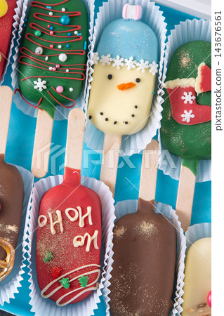 Christmas dessert. Sweet food. Cheesecake on a stick in the shape of ice cream. Children's treat in winter. Candy Christmas tree, snowman, deer and Santa Claus. Gingerbread cookies Christmas dessert. Sweet food. Cheesecake on a stick in the shape of ice cream. Children's treat in winter. Candy Christmas tree, snowman, deer and Santa Claus. Gingerbread cookies 143676561