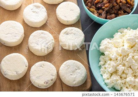 Cheesecakes made from cottage cheese and raisins. Prepare food for breakfast. Syrnik pancakes. Round cheese cake on black background. Cheesecakes made from cottage cheese and raisins. Prepare food for breakfast. Syrnik pancakes. Round cheese cake on black background. 143676571