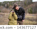 Father helping his preteen son looking through binoculars at forest scenery during autumn travel 143677127