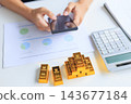 Selective focus on gold bars with background of hands using smartphone for gold trading, analyzing or managing. Concept for wealth management, asset protection, and financial planning. 143677184
