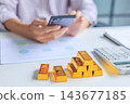 Selective focus on gold bars with background of hands using smartphone for gold trading, analyzing or managing. Concept for wealth management, asset protection, and financial planning. 143677185